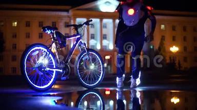 发光的自行车倒映在水中.. 一个穿着发光鞋的男人围着一辆未来派自行车跳舞。